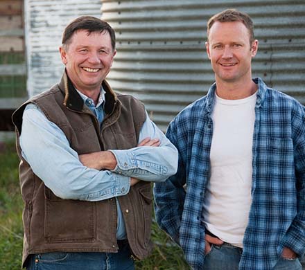 Two men in front of silage silo