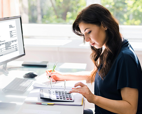 Business Woman at desk with computer, using calculator